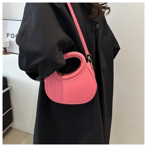 Detailansicht der rosafarbenen Faltenhandtasche mit Rundgriff und Riemen am Modell