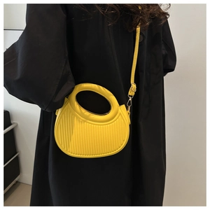Detail der leuchtend gelben Halbmond-Tasche mit Streifentextur und rundem Griff am Model