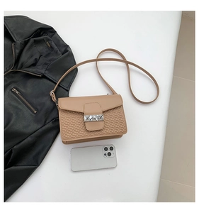 Detail of khaki crossbody bag featuring embossed heart patterns and silver pyramid lock
