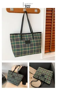 Detail of green and gray checkered fabric texture and black leather straps on tote bag