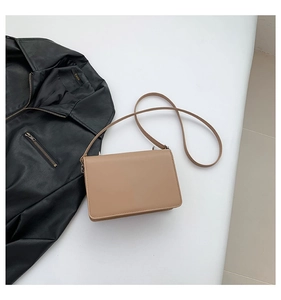 Chic khaki square shoulder bag in leather texture displayed with a black biker jacket