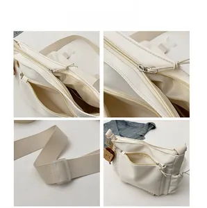 Détails du sac bandoulière en nylon beige avec fermetures éclair, sangle et charm d'ours