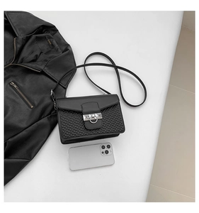 Detail view of woven texture and silver ring clasp on a minimalist black crossbody bag