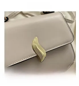 Gros plan du fermoir doré ondulé et des coutures fines sur le sac en cuir beige de luxe
