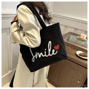 Detailed texture of black corduroy tote bag with smile print and red heart design