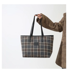 Close-up of vintage plaid tote bag featuring checkered wool texture and black logo patch