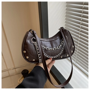 Gros plan du sac baguette marron foncé à motif crocodile avec chaîne argentée et rivets