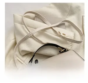 Détail de la bandoulière de sac à main beige avec finitions métalliques dorées