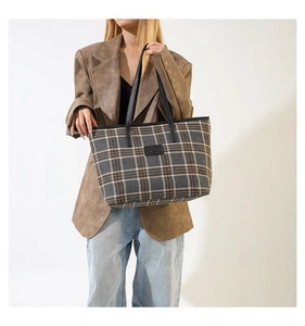 Detail of a large vintage checkered tote bag showing material texture and shoulder fit