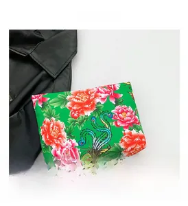 Detailed view of green nylon clutch bag with traditional peony and phoenix floral prints