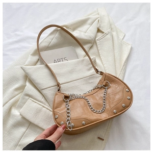 Détail du sac à bandoulière croissant avec texture pierre, rivets et chaîne argentée