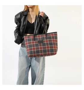 Detail of checkered tote bag featuring red and grey patterns with black handles