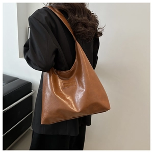 Detail showing the brown faux leather texture and fashion brand tag on the shoulder bag