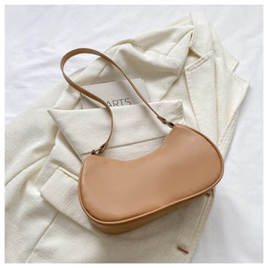 Gros plan sur le sac hobo croissant marron clair en cuir lisse sur un blazer blanc