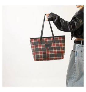 Detail of checkered knit tote bag featuring red and grey patterns with black leather handles