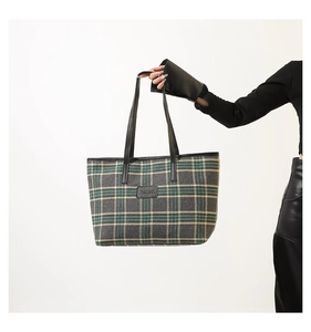 Close-up of a large plaid tote bag with dark green check pattern and leather logo