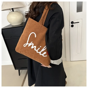 Detail of caramel corduroy tote bag showing the Smile print and textured fabric