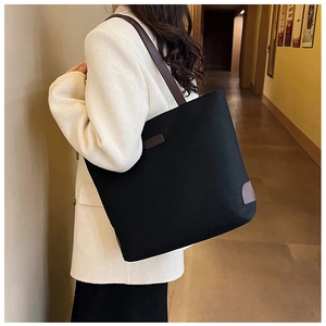 Detail view of durable black canvas tote with leather shoulder straps and fashion logo