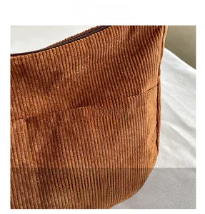 Detail of brown corduroy fabric texture and leather Sport label on the crossbody bag
