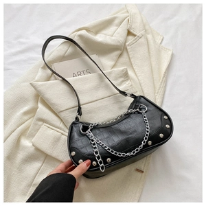 Détail de la texture crocodile et de la chaîne argentée sur un sac à main noir épuré