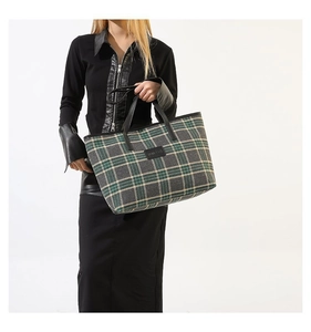 Detail of checkered tote bag featuring green and yellow patterns with black leather straps