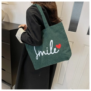 Detail of dark green corduroy tote bag with smile print and wide shoulder strap