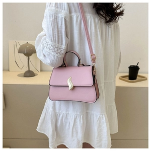 Détail du sac bandoulière rose avec boucle S dorée porté par un mannequin en robe dentelle