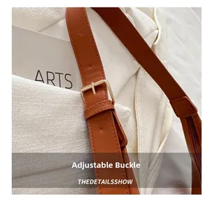 Close-up of golden metal buckle and adjustable brown leather strap on minimalist bucket bag
