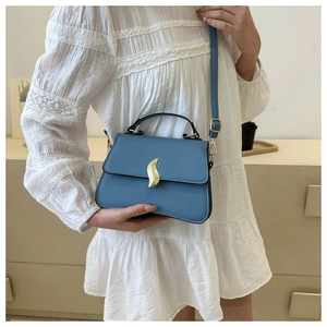 Détail du petit sac carré bleu ciel avec fermoir feuille dorée sur fond d'intérieur