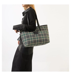 Detail of green plaid tote bag featuring black leather straps and brand logo patch