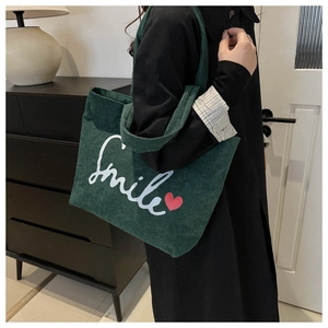 Detailed close-up of dark green corduroy tote bag texture with Smile embroidery