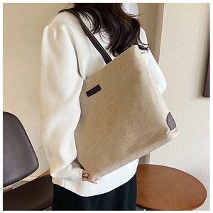 Detail of canvas tote bag with brown leather patch and shoulder straps in cozy cafe setting