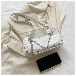 Détail de la texture crocodile blanche avec chaîne argentée et rivets sur le sac à main