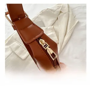 Close-up of smooth gold metal zipper closure on a deep brown faux leather bucket bag