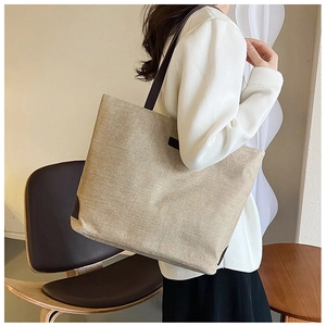 Lifestyle shot of large beige canvas tote bag with brown leather straps on model
