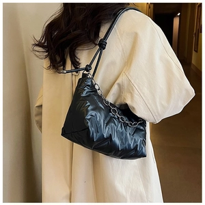 Détail du sac bandoulière noir matelassé avec tissu plissé et chaîne en métal argenté