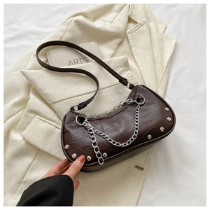 Détail du sac à main marron foncé à motif crocodile avec chaîne et rivets argentés