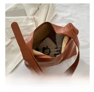 Detail showing high capacity of caramel brown hobo bag with daily essentials inside