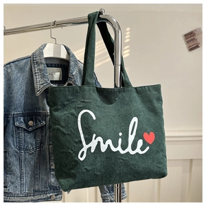 Detailed texture of green corduroy tote bag featuring a white Smile print with heart