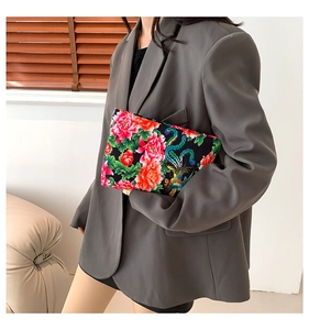 Detailed view of the vibrant ethnic floral print and phoenix pattern on the flat clutch bag