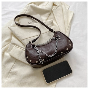 Détail du sac hobo marron foncé avec texture croco, chaîne argentée et rivets sur blazer