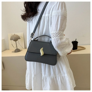 Détail du sac à bandoulière gris foncé avec fermoir métallique doré sur le rabat en cuir