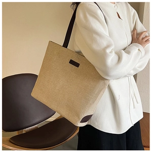 Close-up of beige tote bag showing canvas texture, leather handles and reinforced corners