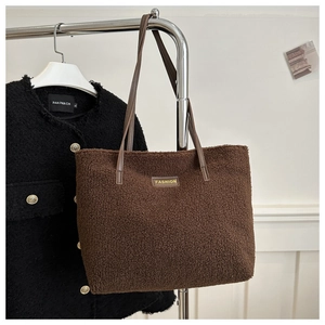 Detalle del bolso tote de felpa marrón oscuro con textura de borrego y asas de cuero