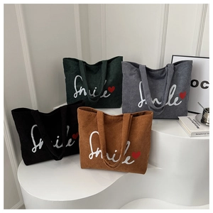 Macro view of four colorful corduroy tote bags with Smile text on minimalist white stand