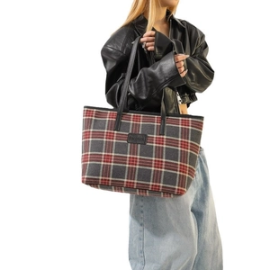 Classic red plaid fabric tote bag with black leather straps shown on a model