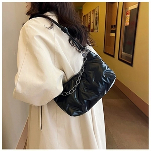 Détail du sac à épaule matelassé noir avec texture brillante et chaîne en argent