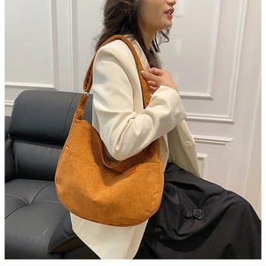 Brown corduroy hobo bag with Sport label shown on a model in a stylish indoor setting