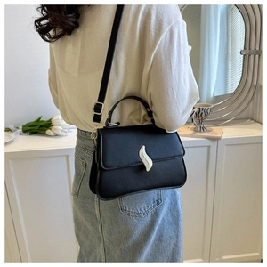 Détail du sac à main en cuir mat noir avec boucle argentée porté avec chemise