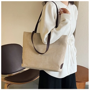 Detail of minimalist beige canvas tote bag with brown leather straps and reinforced base